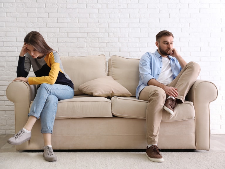 Couple Sitting On Couch Unhappy Before Seeing a Relationship Counselor in San Diego, CA